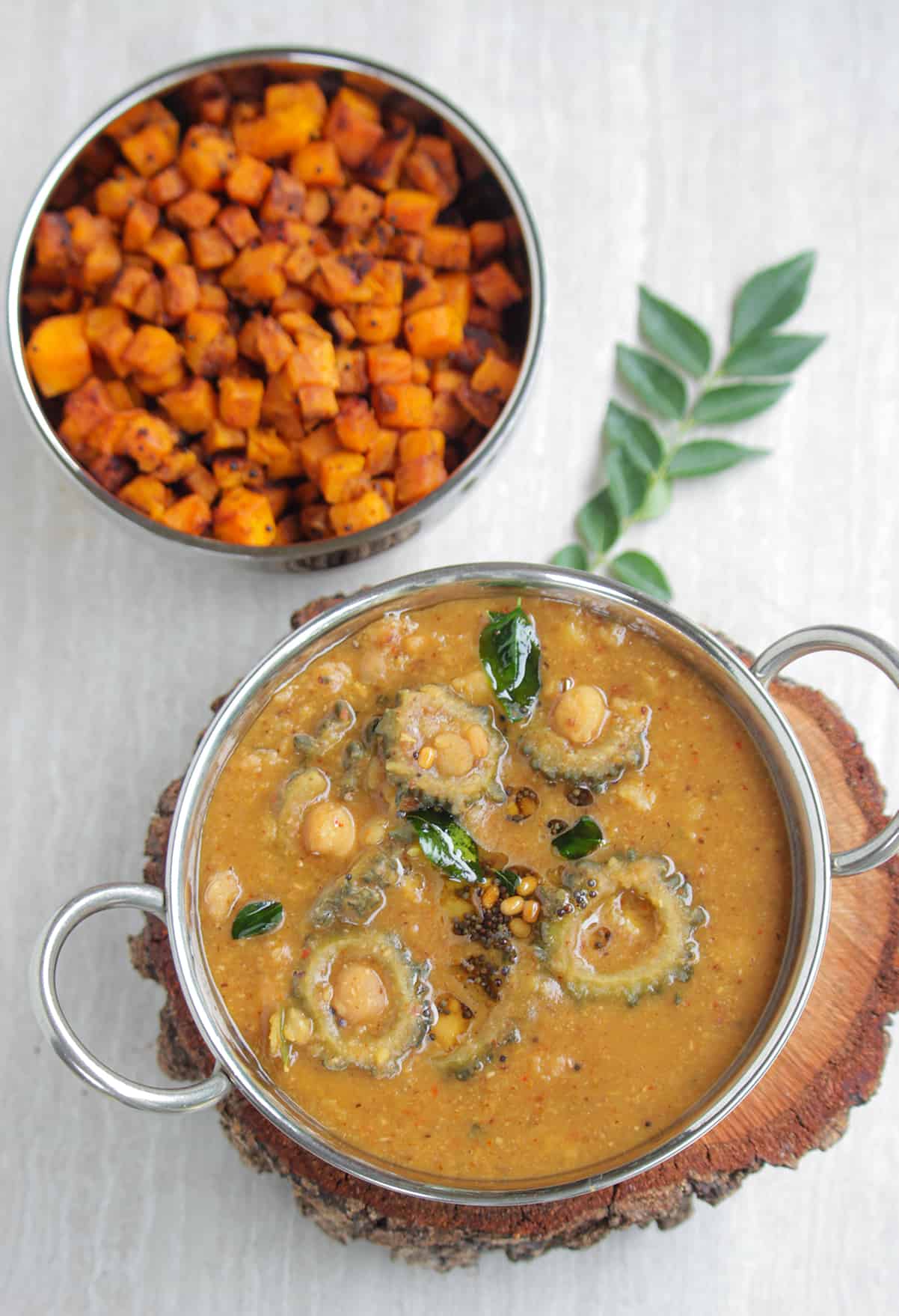 bitter gourd and chick peas stew in a bowl with sweet potato curry in background