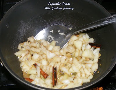Frying Fennel seeds, Cinnamon, Cardamom and chopped onions and cooking in a Pan.