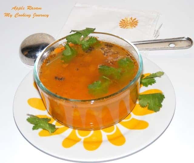 Apple Rasam decorated with cilantro in a glass bowl