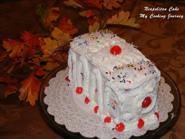 Neapolitan Cake decorated with cherries and sprinkles