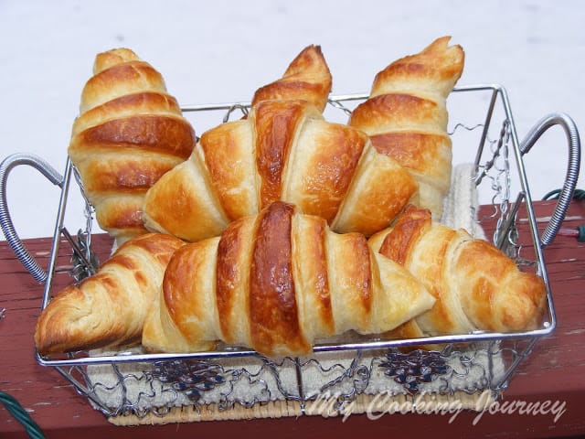 Flaky Butter Croissants stacked in a metal basket
