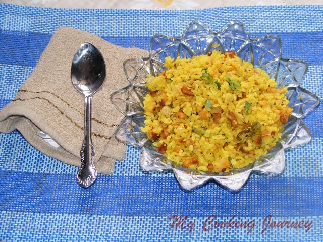 Kanda Batata Poha in a decorative glass bowl with a spoon on the side