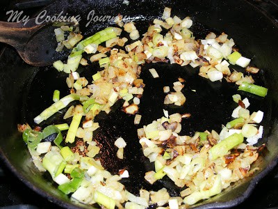Adding garlic and scallions in a pan