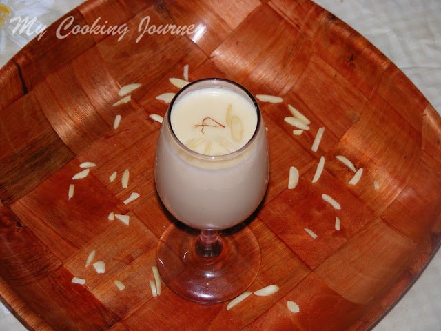 Badam Kheer in a glass cup with a brown tray in the bottom
