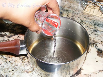 Adding rose water in the pan.