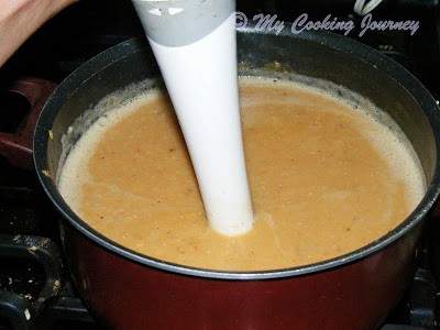 Blending the lentil soup using an immersion blender