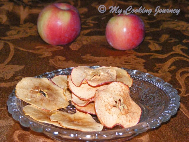 Baked Apple Chips in a plate with 2 apples in background