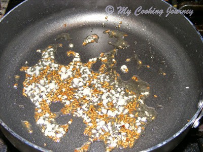 Frying cumin seeds in a pan.