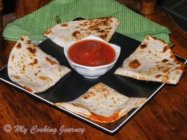 Pizzadilla served in a tray with sauce