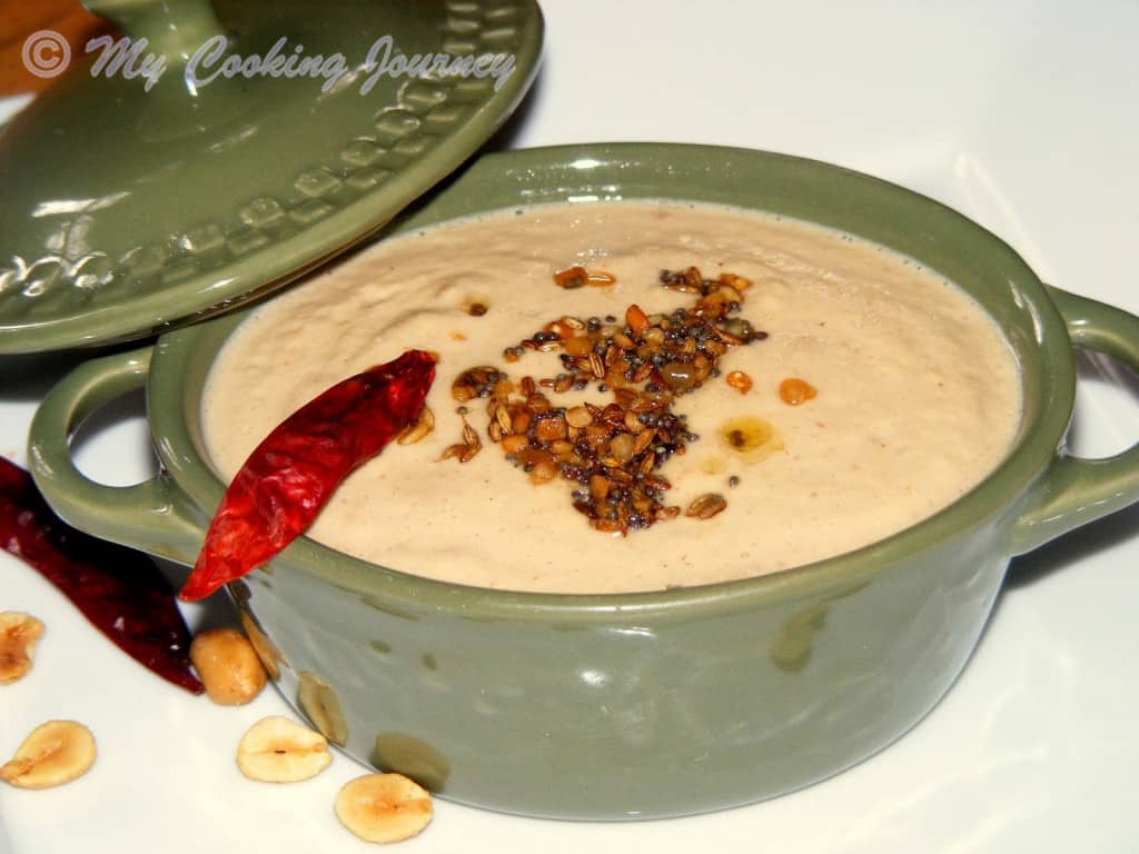 Peanut chutney in a bowl decorated with red chilies.