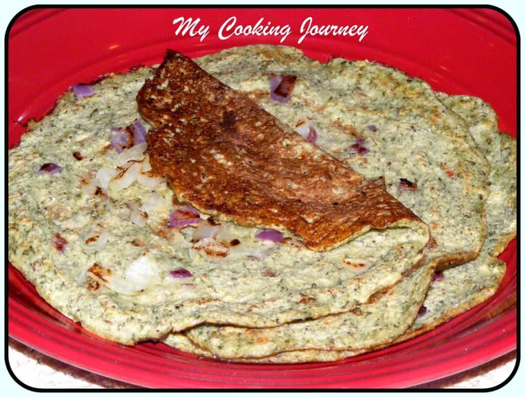 Andhra Pesarattu served in a plate with some onion on it