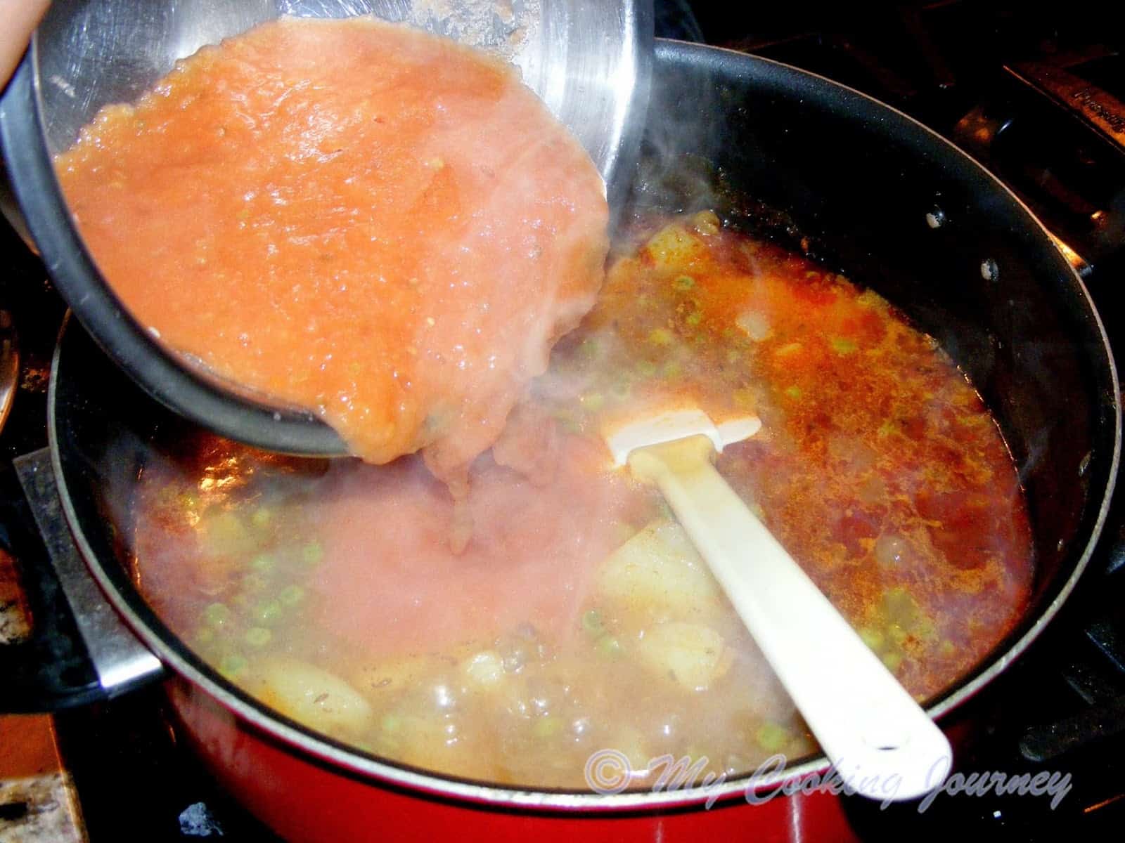 adding tomato paste to boiling gravy