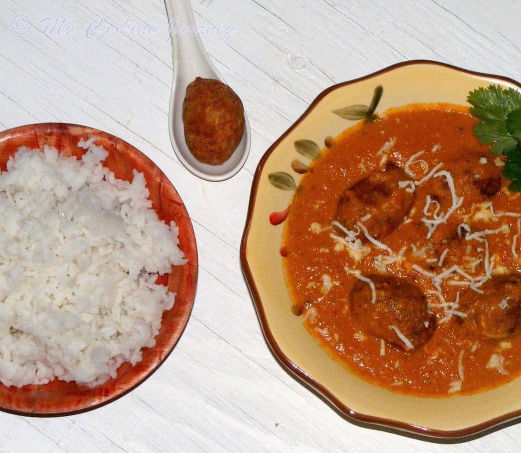 Malai Kofta with gravy and rice on the side. Fried Kofta in the spoon.