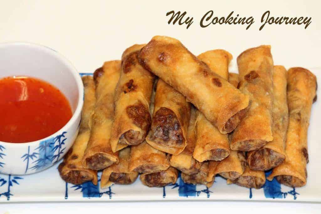 Chinese Spring rolls stacked with dipping sauce in the sauce.