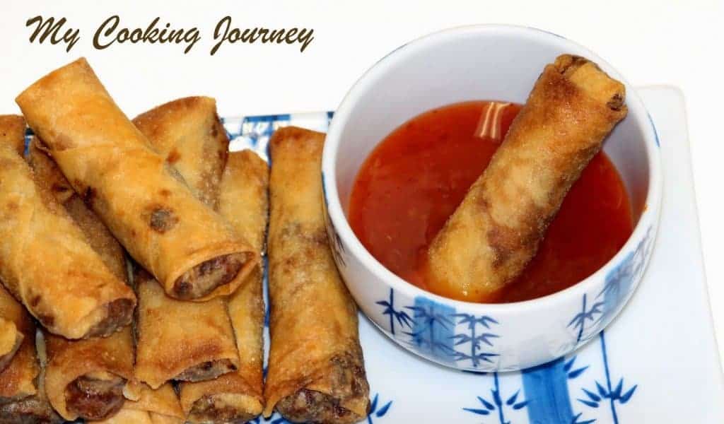 Vegetable and Tofu Spring Rolls stacked in a plate with a dipping sauce in a bowl