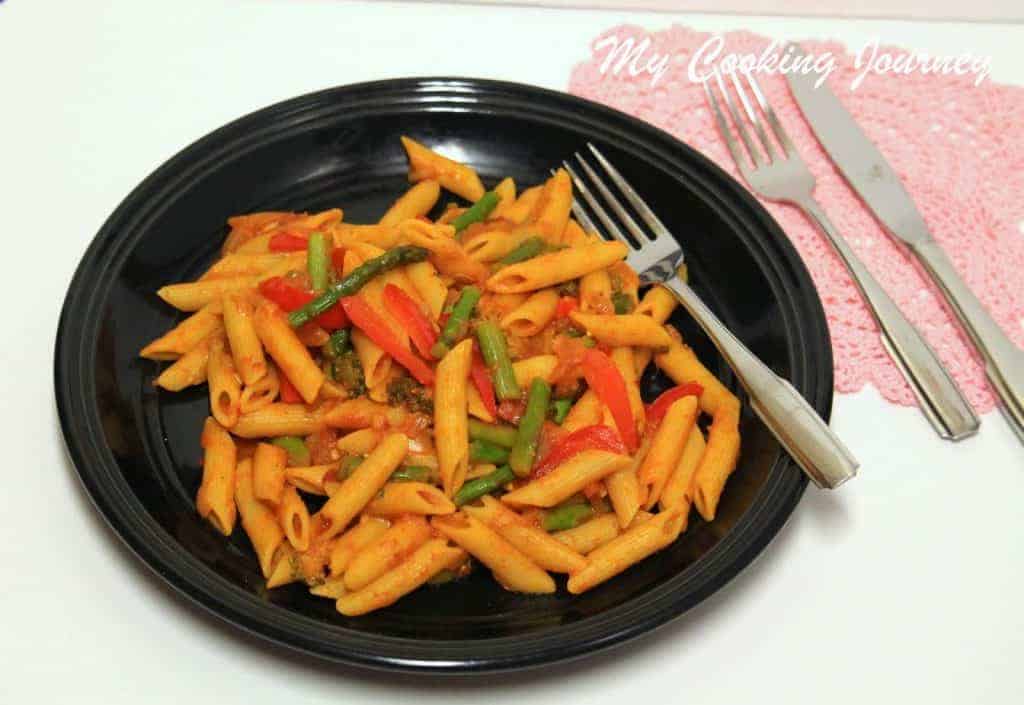 Pasta Primavera in a black plate with fork,