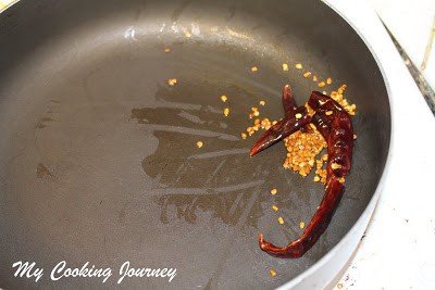 Tempering fenugreek seeds and red chilies in a pan