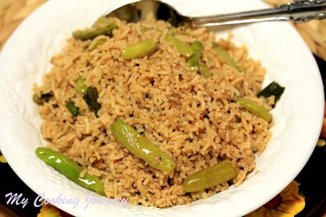 Masala Bhaat served in a plate with a spoon on the side