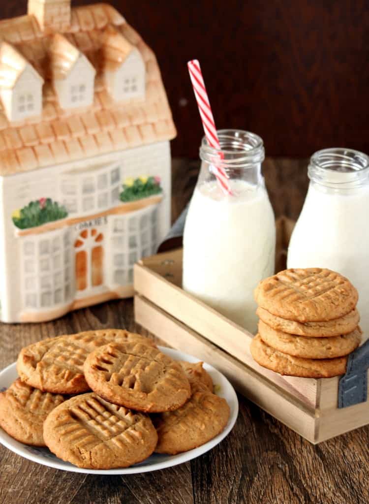 Peanut butter cookies arranged with cookie tin and milk in background