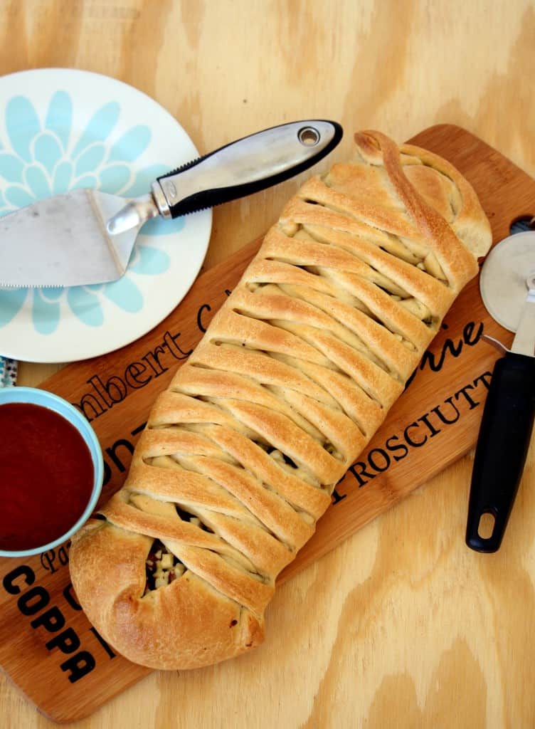 Vegetable Stuffed Braided Bread served with pizza cutter with sauce
