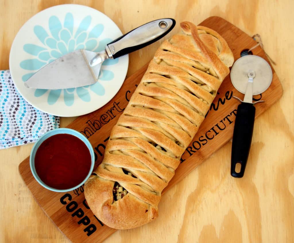 Spicy Braided Stuffed Bread on a wooden board with sauce in a bowl