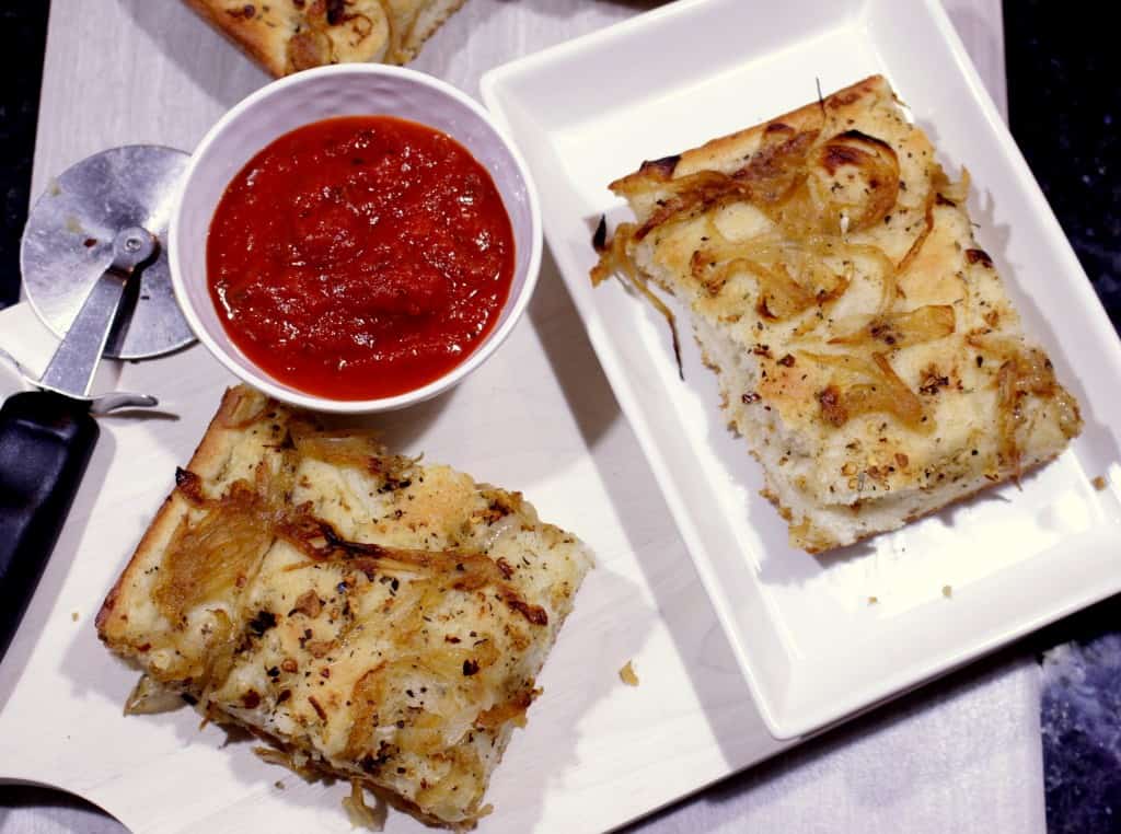 Focaccia with Herbed Oil and Caramelized Onions in a tray with dipping Sauce