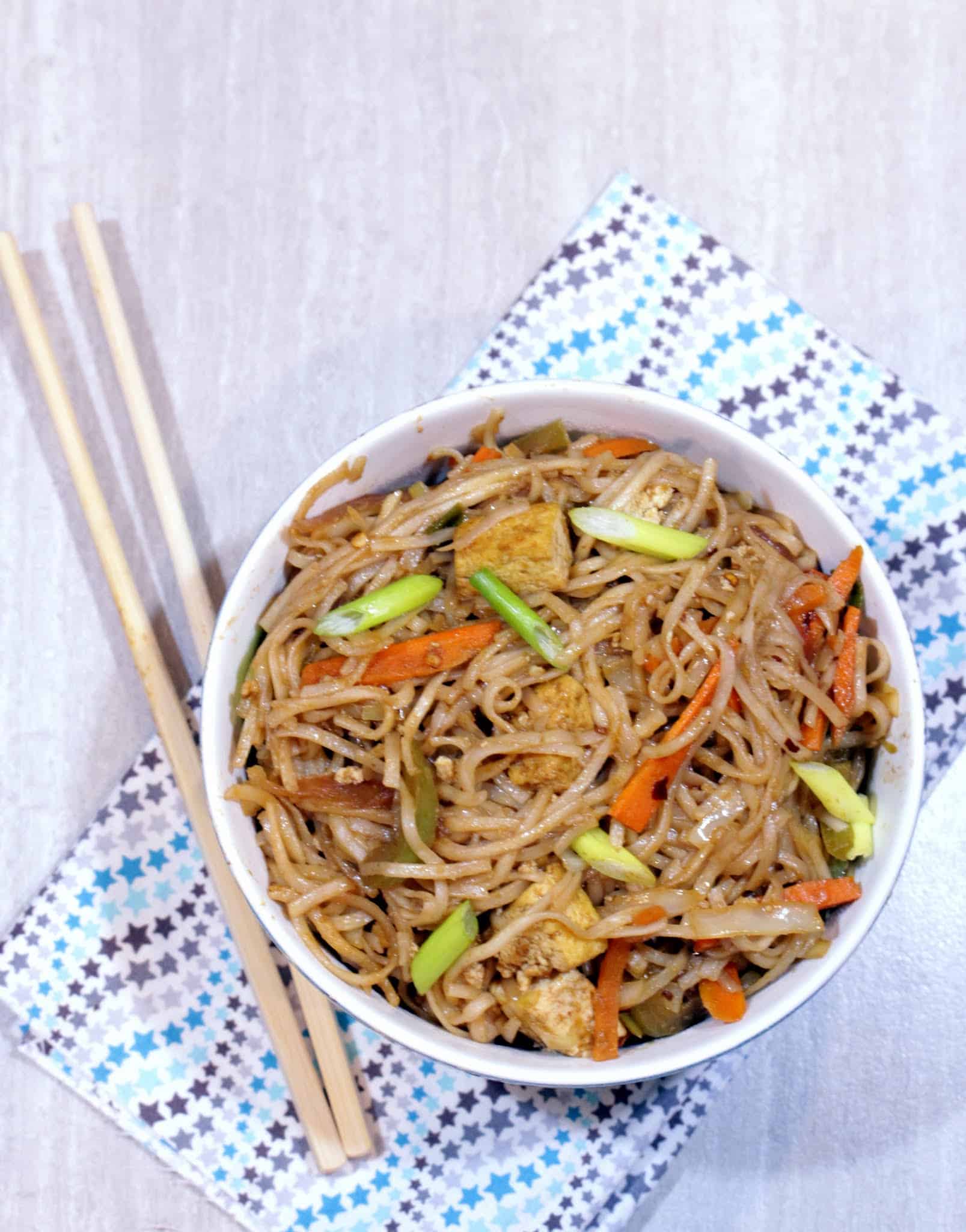 Hakka Noodles in a bowl with chopsticks on side