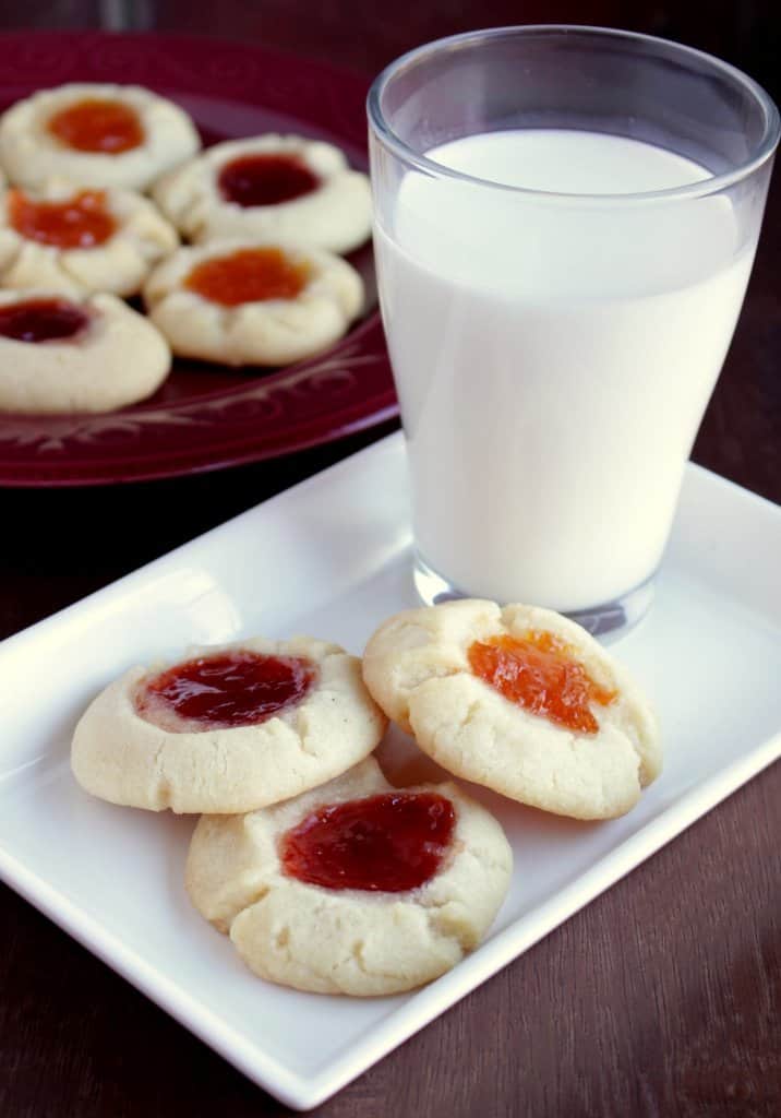 some jam thumbprint cookies with glass of milk