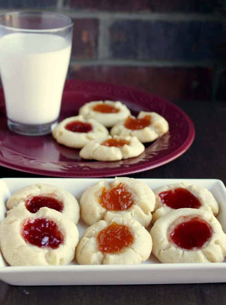 Jam Thumbprint Cookies on a red  and white plates with milk on the side.