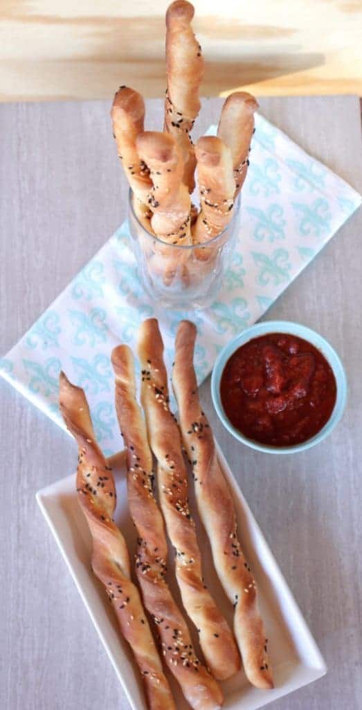 breadstick on plate and in a glass with tomato sauce on side