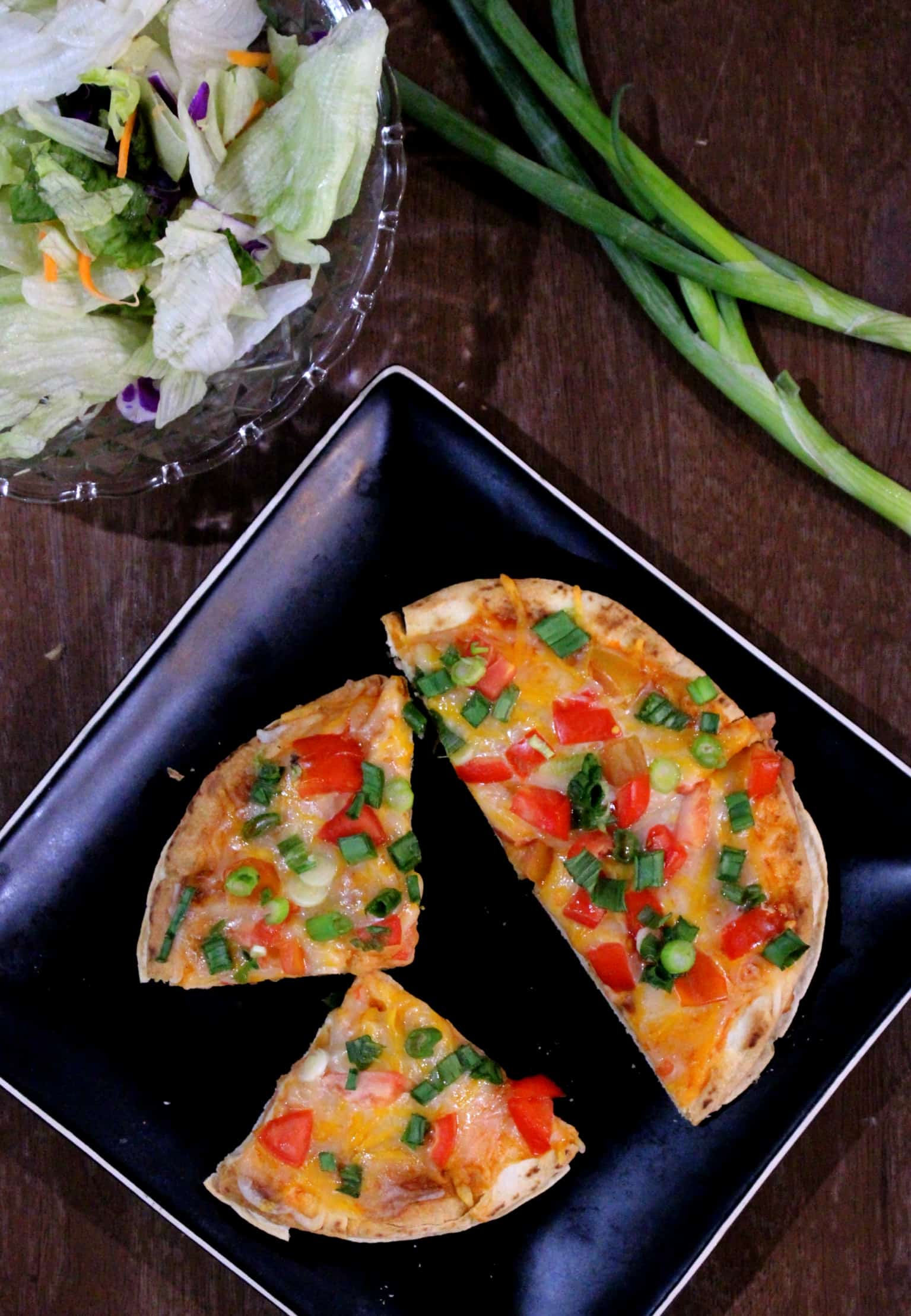 Mexican Pizza in a black dish with sspring onions