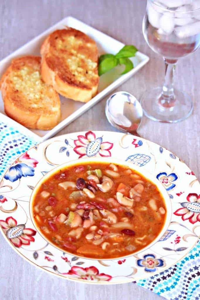 Vegetarian15 Bean Soup in a floral bowl with bread, glass and spoon on the side