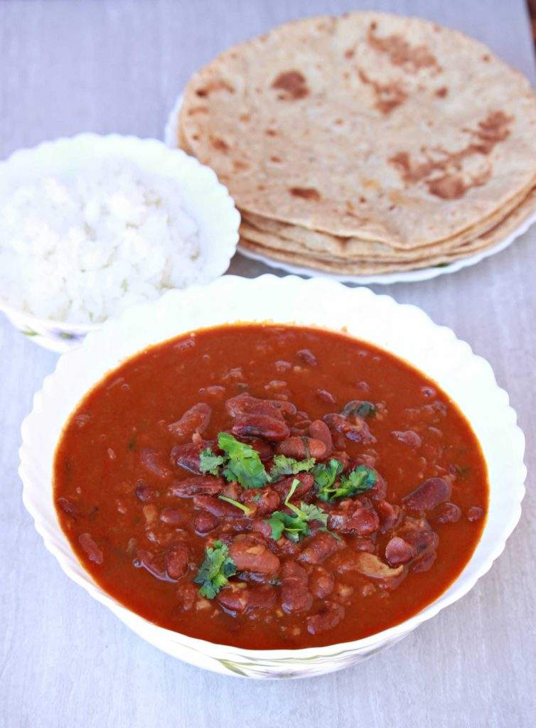 Instant Pot Rajma Masala in a white bowl with roti and rice on the side