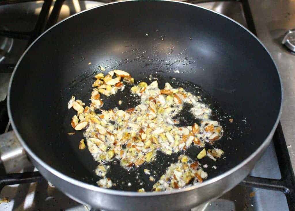 frying nuts in ghee in a black pan