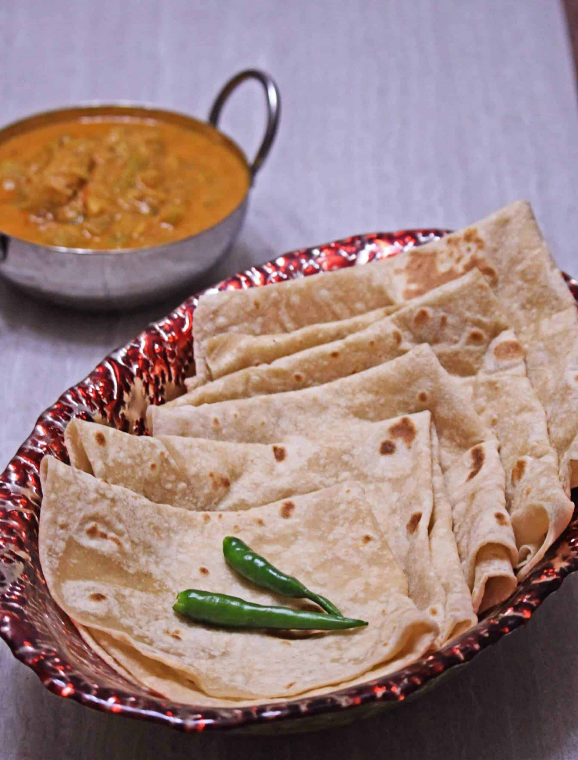 stack of roti on a bowl with green chilies on top