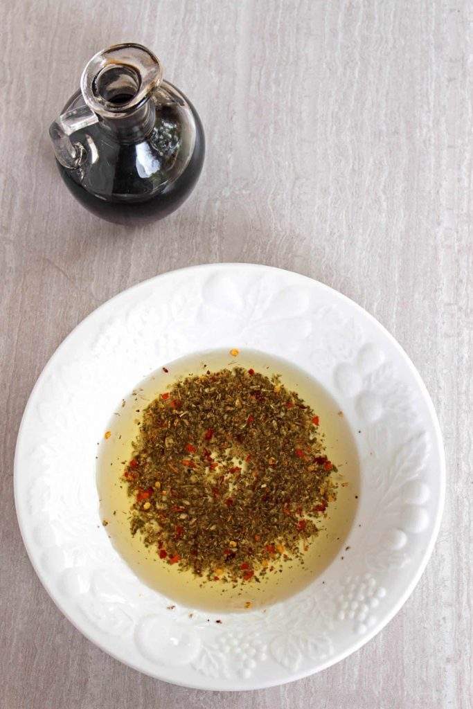 Garlic and herb dipping oil in white bowl