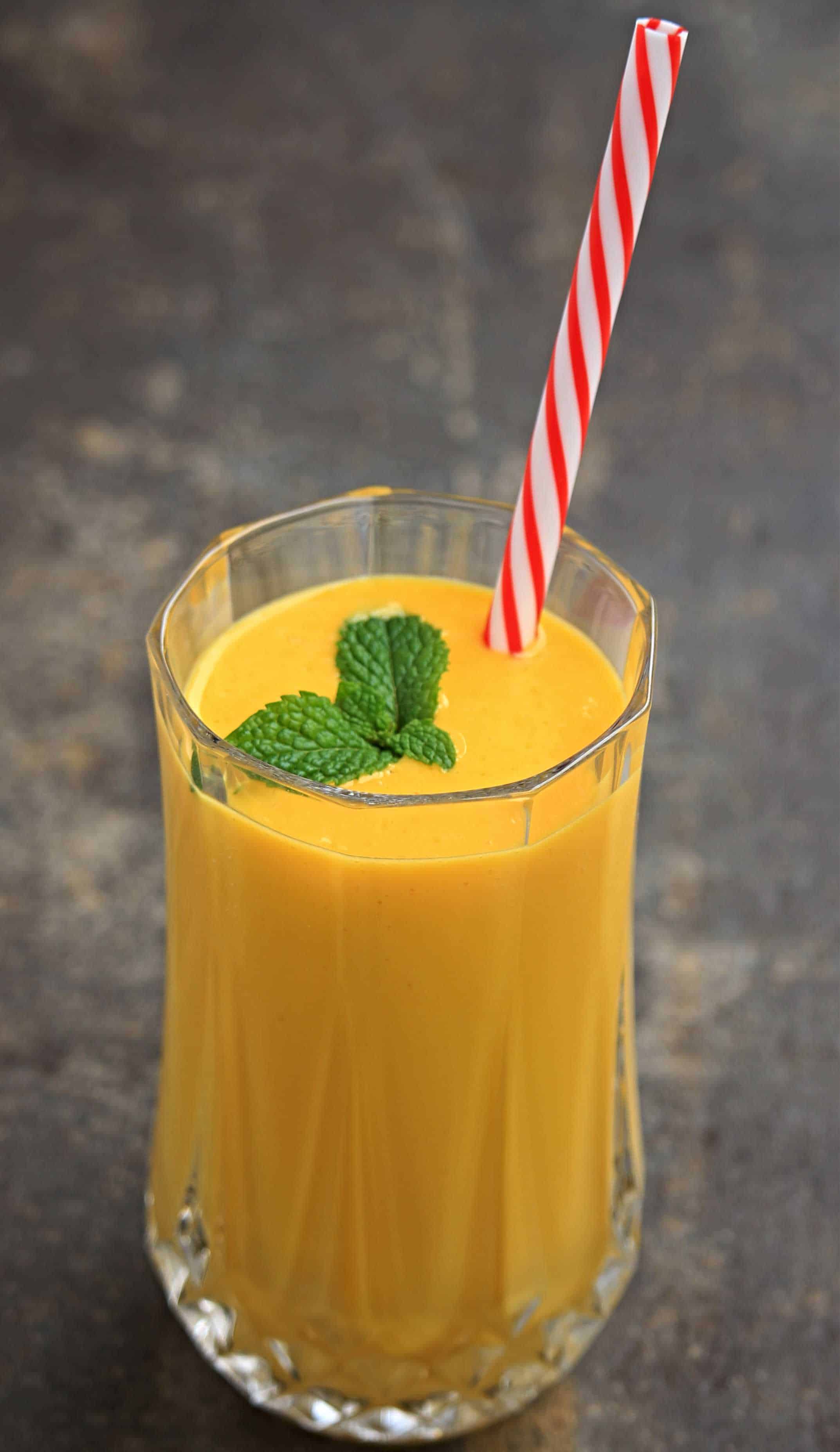 mango lassi in a tall glass with straw