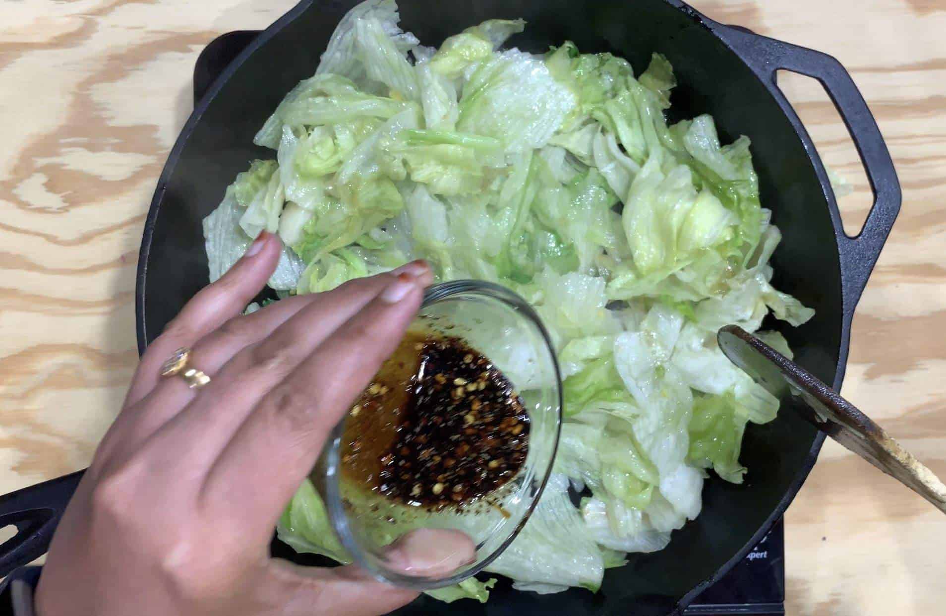 Adding sauce to lettuce stir fry