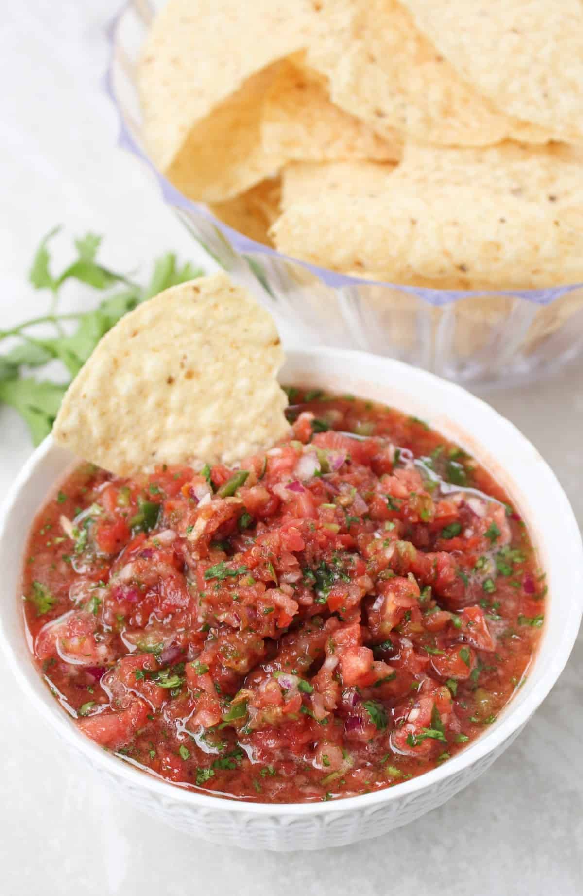 Tomato salsa in a white bowl with tortilla chips