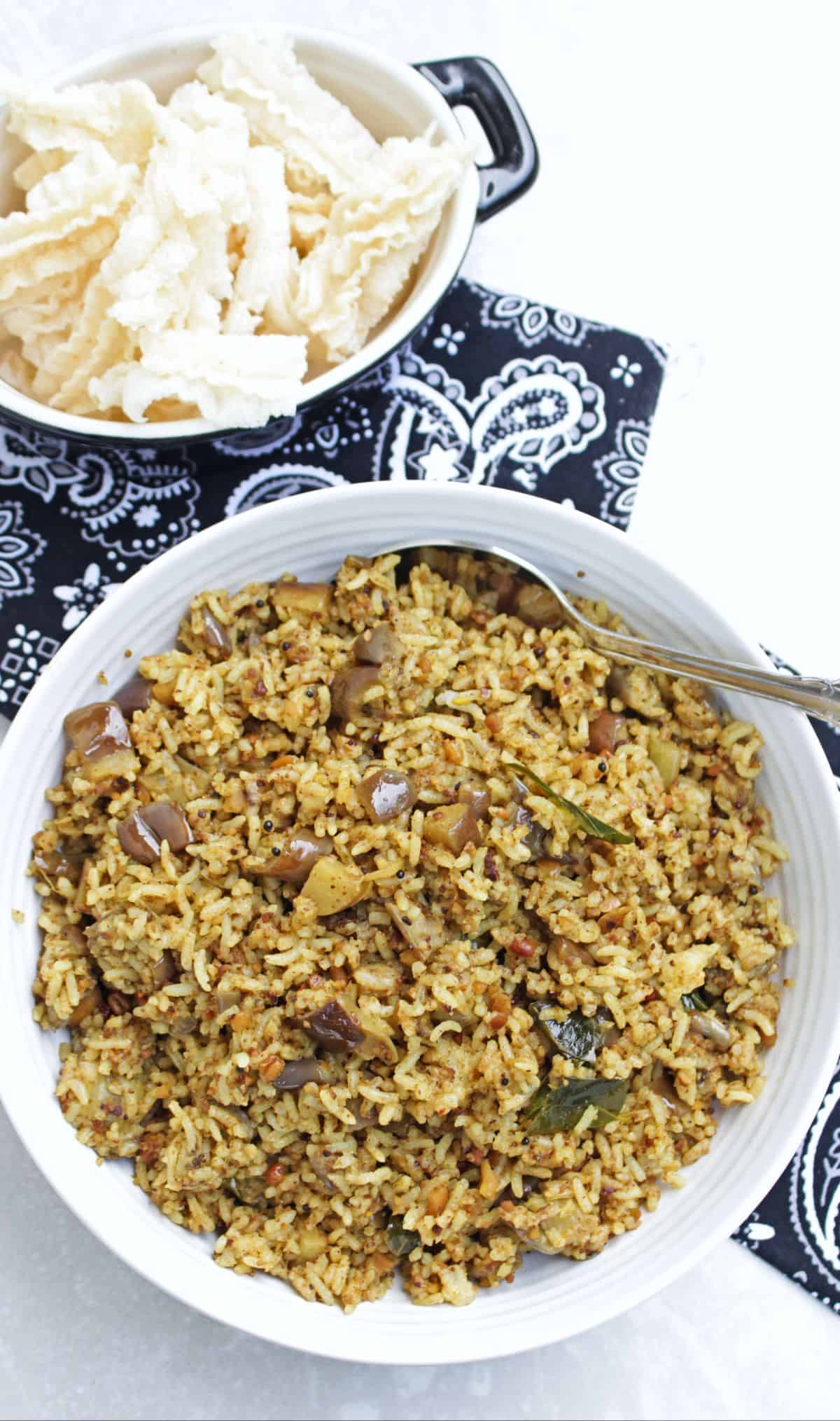 Brinjal rice served with vadam in a white bowl