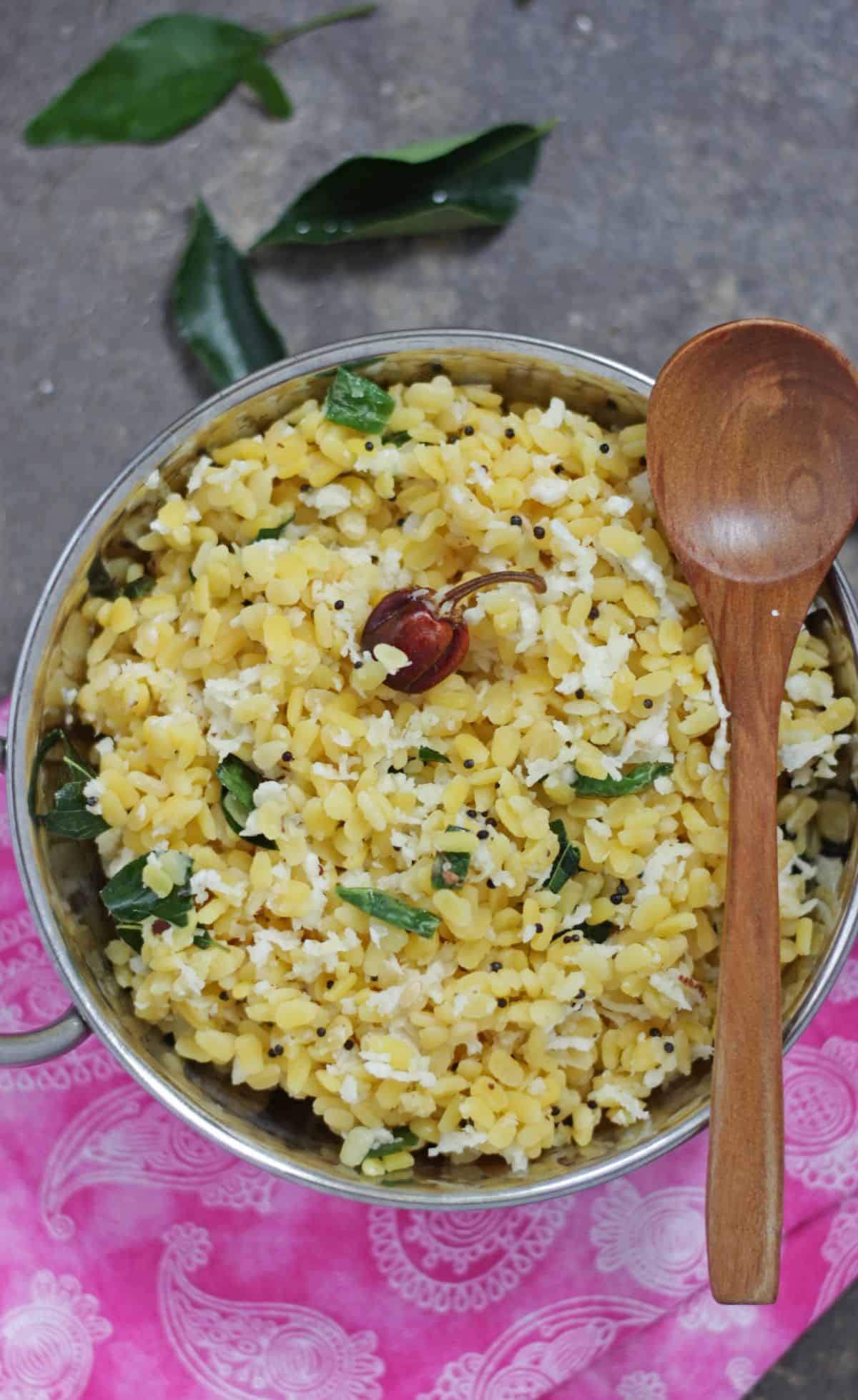 Moong dal sundal in steel bowl with a wooden spoon on top