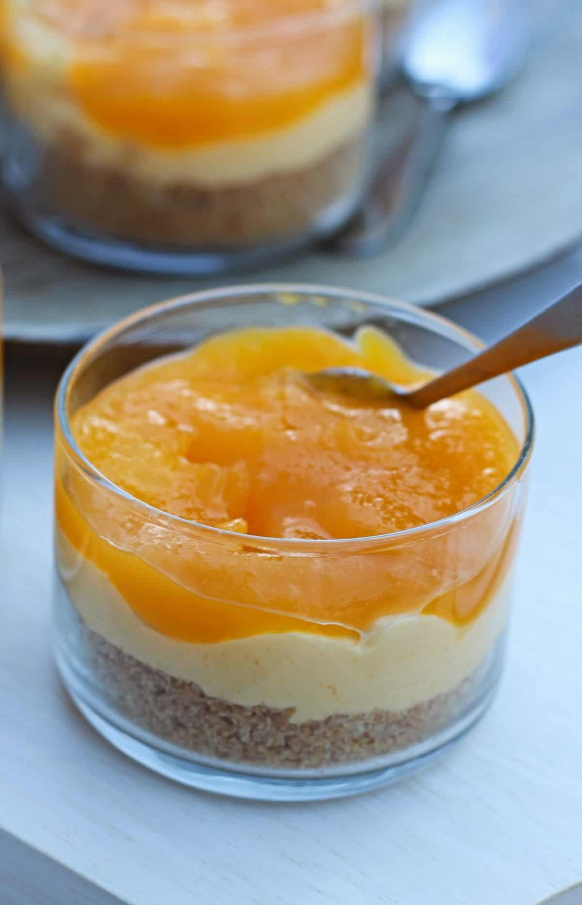 Mango cheese cake in a glass cup with spoon