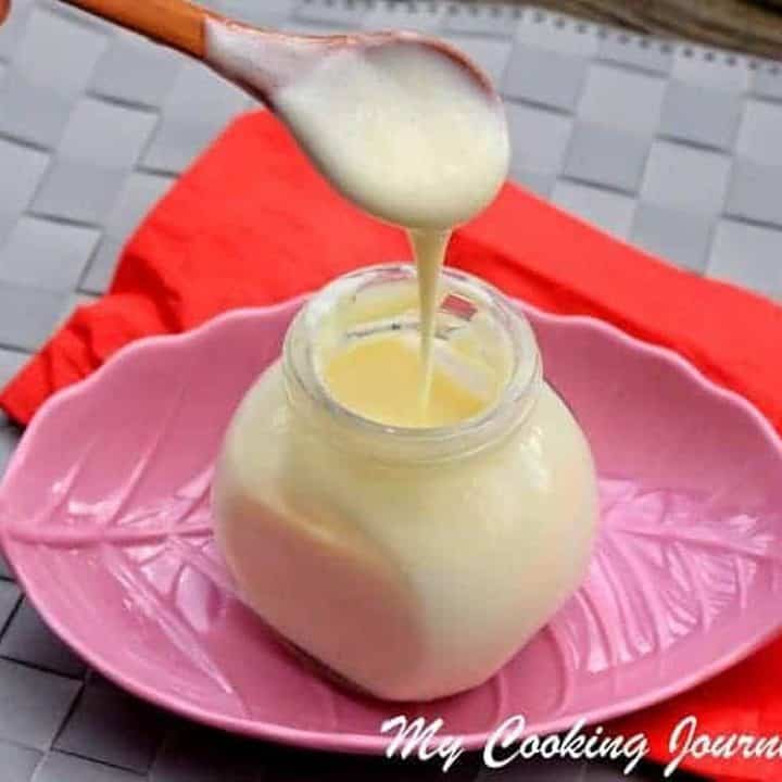 Condensed Milk in a glass Jar with some on the spoon - Featured Image