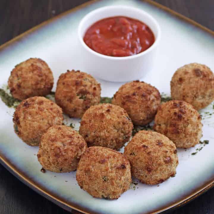 Arancini in a white plate with sauce on the side - Feature Image